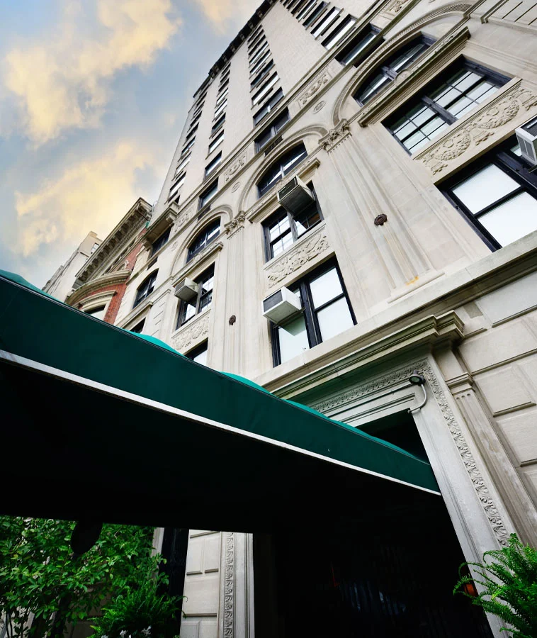 A tall, elegant hotel building with classic architectural details and a green awning at the entrance, viewed from the street level - Out of Town Patient Resources in New York, NY